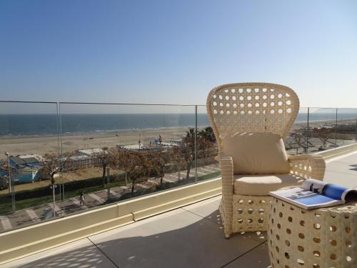 a chair sitting on a balcony with a view of the beach at The Promenade Luxury Wellness Hotel in Riccione