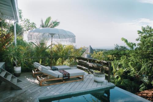 a deck with a chair and an umbrella and a pool at White Tortoise Eco Villa's in Uluwatu