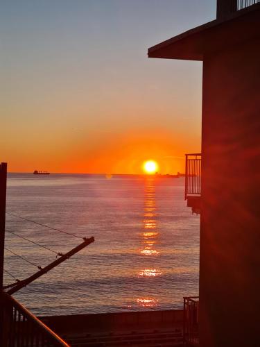a sunset over the water with the sun setting in the distance at Home Salerno Gateway AmalfiCoast in Salerno