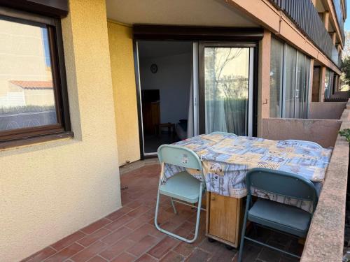 une table et deux chaises assises sur une terrasse dans l'établissement Appartement RDC 6 pers, à 20m plage Grazel, Gruissan - FR-1-784-10, à Gruissan