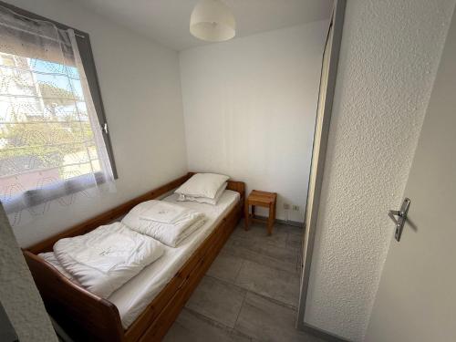 un petit lit dans une chambre avec une fenêtre dans l'établissement Appartement RDC 6 pers, à 20m plage Grazel, Gruissan - FR-1-784-10, à Gruissan