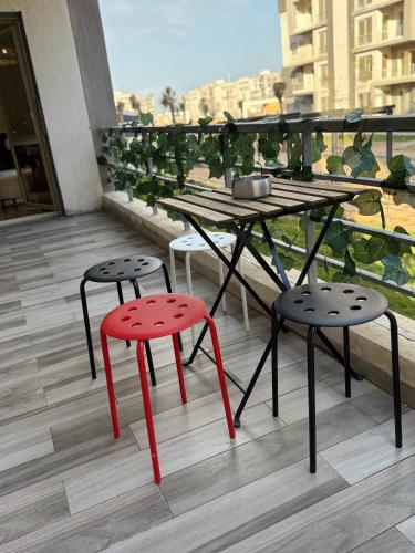a table and two stools with red legs on a balcony at JRE-EG modern aprt01SheikhZayed 5min to ArkanPlaza in Sheikh Zayed