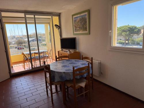 Cette chambre dispose d'une table, d'une télévision et d'un balcon. dans l'établissement Studio Cabine à Gruissan pour 4 Pers. avec Loggia et Parking Privé – Résidence Voile d'Oc - FR-1-784-11, à Gruissan