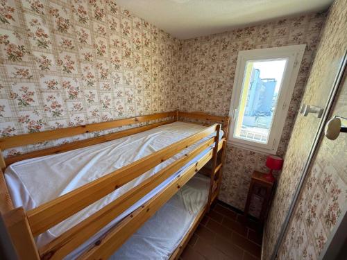 - une chambre avec un lit en bois dans une pièce avec du papier peint dans l'établissement Studio Cabine à Gruissan pour 4 Pers. avec Loggia et Parking Privé – Résidence Voile d'Oc - FR-1-784-11, à Gruissan