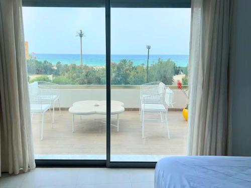 a bedroom with a view of a patio with a table and chairs at Luxueux appartement en bord de mer in Sousse