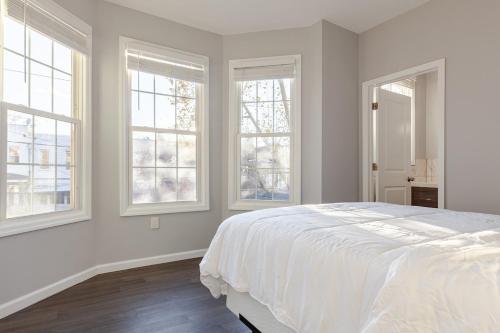 a white bedroom with windows and a large bed at Bright & Cozy Jersey City Retreat in Jersey City
