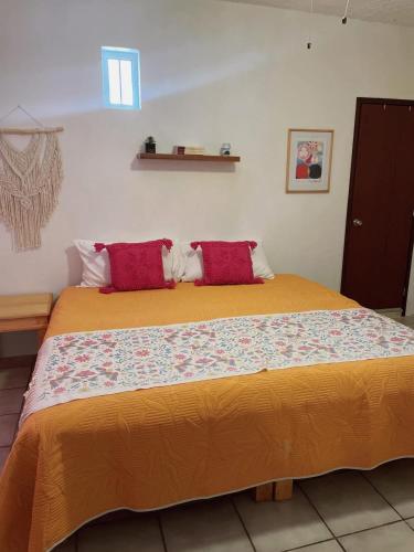 a bedroom with a large bed with red pillows at Casa Jardín in Tequila