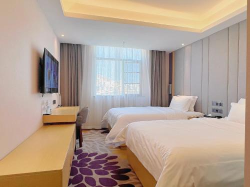 a hotel room with two beds and a television at Lavande Hotel Shenzhen International Convention and Exhibition Center Fuhai West Subway Station in Shenzhen