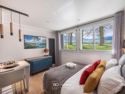 une chambre avec un lit, un bureau et des fenêtres dans l'établissement Studio Pâquier - Lac d'Annecy, à Annecy