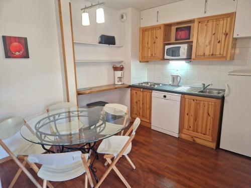 une cuisine avec une table en verre et des appareils électroménagers blancs dans l'établissement Appartement cosy 6 pers, 2 chambres, à 30m télécabine, proche commerces, balcon et casier à skis - FR-1-265-329, à Modane