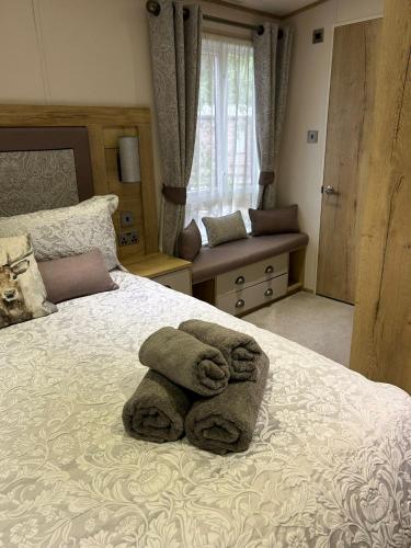 a bedroom with a bed with towels on it at Lodge 2 The Wee Hut Aviemore in Aviemore
