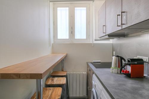 une cuisine avec des armoires blanches et un comptoir en bois dans l'établissement Appartement moderne avec 2 chambres, cœur de Lyon, à Lyon