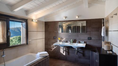 a bathroom with a sink and a tub and a mirror at Villa Vittoria 8 by Massimo Villas in Gratteri