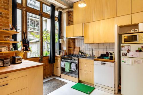 une cuisine avec des armoires en bois et un réfrigérateur blanc dans l'établissement GuestReady - Midcentury Maisonette in the 10th, à Paris