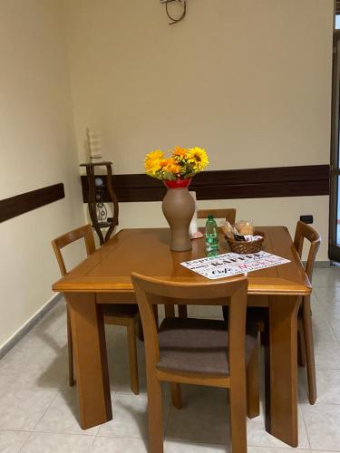 a wooden table and chairs with a vase with flowers on it at Casa Alleria in Battipaglia