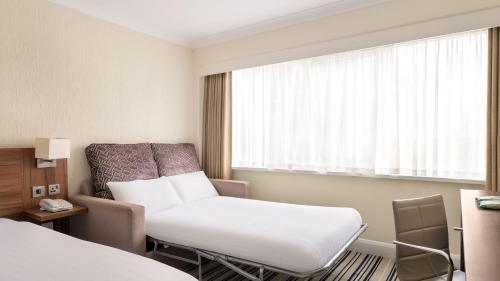 a room with a bed and a chair and a window at Holiday Inn Ipswich by IHG in Ipswich