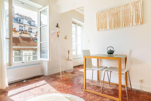 une table et des chaises dans une pièce avec une fenêtre dans l'établissement GuestReady - Superb haven of peace in Marais, à Paris