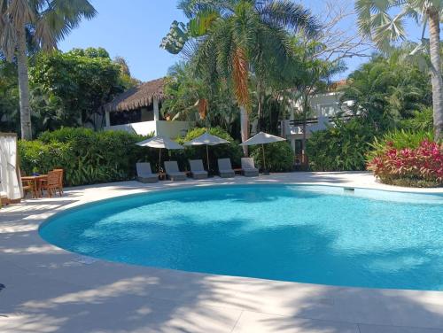 a large swimming pool with chairs and umbrellas at Lovely modern beach Villa in Cruz de Huanacaxtle