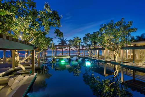 uma imagem de uma piscina de resort à noite em Naman Retreat em Da Nang
