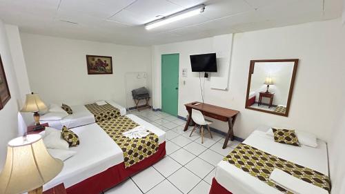 a hotel room with two beds and a desk at La Posadita de Bolonia in Managua