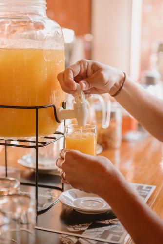 a person is making a glass of orange juice at Puerto Dijama Hotel Boutique in Carmelo
