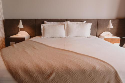 a bedroom with a large bed with white sheets and pillows at Puerto Dijama Hotel Boutique in Carmelo
