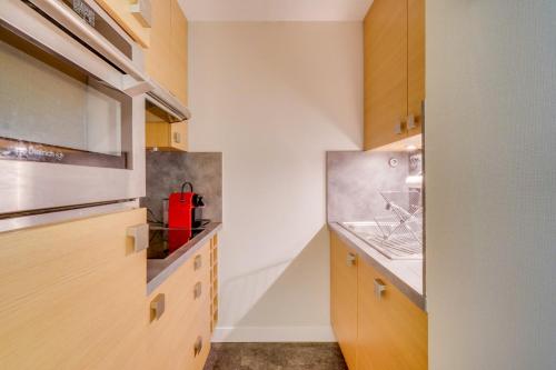 une cuisine avec des placards en bois et un appareil rouge dans l'établissement Studio Cabine avec Terrasse, Accès Plage Pereire – Boulevard de l'Océan, Arcachon, à Arcachon