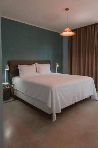 a bedroom with a white bed and a green wall at Puerto Dijama Hotel Boutique in Carmelo
