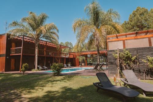 a house with a swimming pool and palm trees at Puerto Dijama Hotel Boutique in Carmelo
