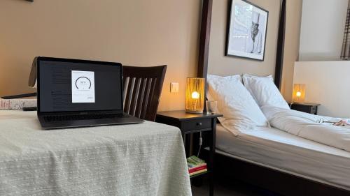 a laptop computer sitting on top of a bed next to a table at Chambre Univers Bocuse - à 200 m de la Légende in Collonges-au-Mont-dʼOr