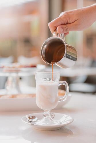 a person pouring chocolate into a cup of coffee at Puerto Dijama Hotel Boutique in Carmelo