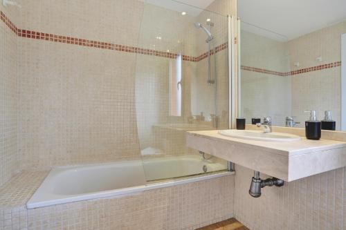 a bathroom with a tub and a sink and a shower at Blue Sky Golf Villas in Antigua