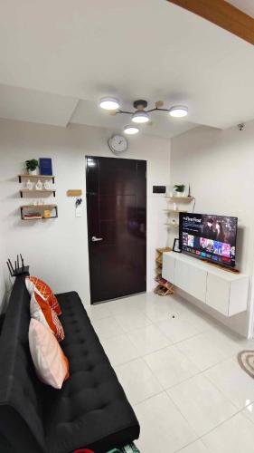 Una sala de estar con un sofá negro y un televisor. en aCed Staycation 6 pax accommodation, en Mandaue