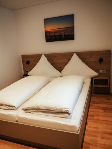 a bed with white sheets and pillows on it at Landgasthof Zum Stern in Hammelburg- Obererthal