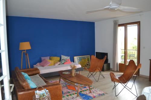 - un salon avec un mur bleu doté d'un canapé et de chaises dans l'établissement Appart 175m2 idéalement situé Stationnement gratuit bas villa, à Ajaccio
