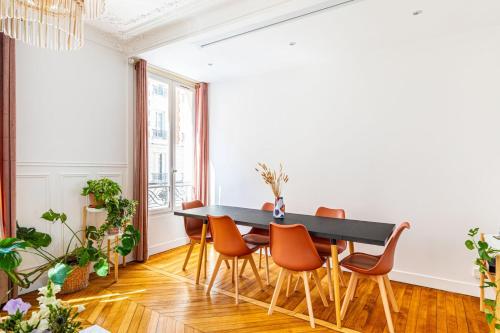 une salle à manger avec une table noire et des chaises orange dans l'établissement GuestReady- Eclectic Delights in Saint-Ouen, à Saint-Ouen