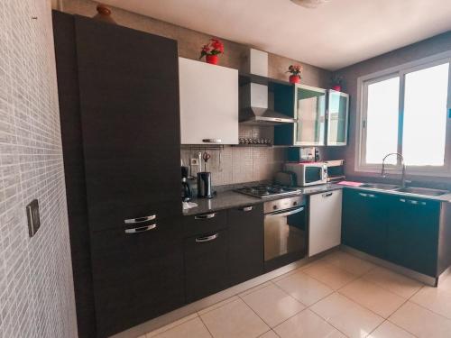 una cocina con armarios negros y azules y una ventana en Luxury and Comfort-Chic Apartment, en Agadir