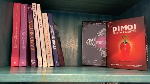 a shelf with some books on a book shelf at Romantique Love Room L Amour sous les Tropiques in Sémussac