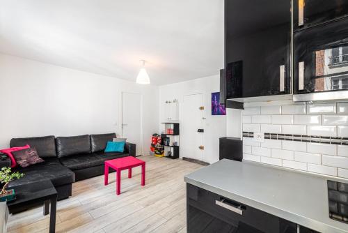 - un salon avec un canapé noir et une table rouge dans l'établissement GuestReady - Charming Canal St-Martin Retreat, à Paris