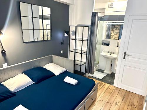 een slaapkamer met een blauw bed en een badkamer bij HSH - LE CHAPELAIS CLICHY MONTMARTe in Parijs
