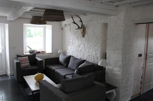 a living room with couches and a stone wall at Le Néblon insolite in Ouffet