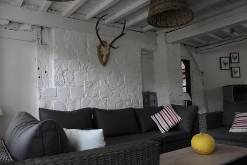 a living room with a black couch and a stone wall at Le Néblon insolite in Ouffet