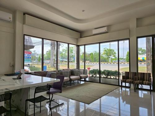 a large room with chairs and a table and windows at The White Residence in Chanthaburi