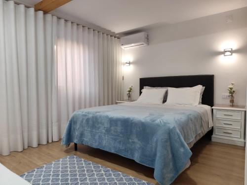 a bedroom with a large bed with a blue blanket at CASA do AÇÔR in Aldeia das Dez