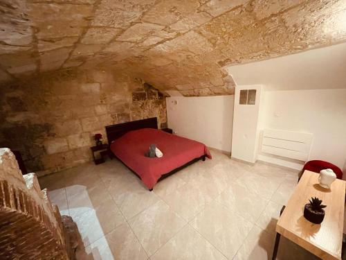 una camera con un letto rosso in una parete in pietra di Luxe Caché Balnéo et Sauna Privés - 372 a Rouen