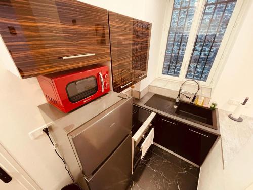une petite cuisine avec un four micro-ondes rouge sur un comptoir dans l'établissement Luxe Caché Balnéo et Sauna Privés - 372, à Rouen