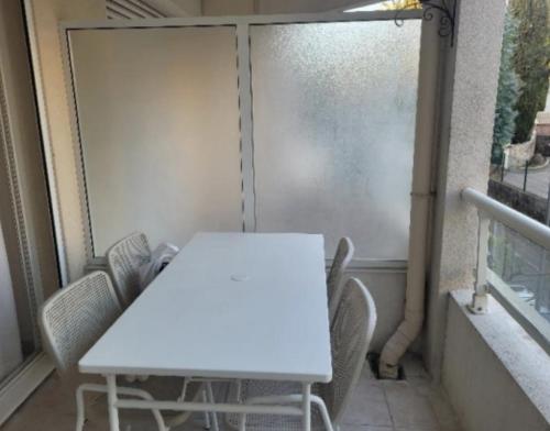 une table blanche et des chaises sur un balcon dans l'établissement centre cannes musiciens, à Cannes