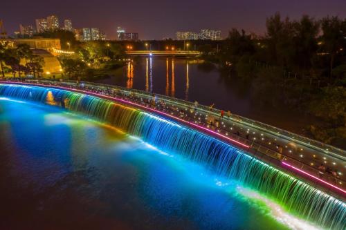 a bridge with colored lights over a river at night at Collection O Cozy 5 Hotel - Near SECC in Ho Chi Minh City