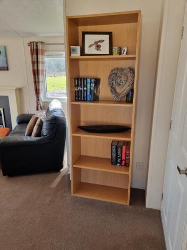 a book shelf in a living room with a couch at Lodge with a stunning view in Beattock