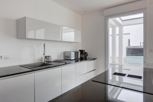 une cuisine avec des armoires blanches et un évier dans l'établissement GuestReady - 2 BR with Terrace near Bordeaux, à Le Bouscat